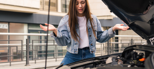 Young worried girl is using a phone to explain the mechanic the problem with a car that she has.